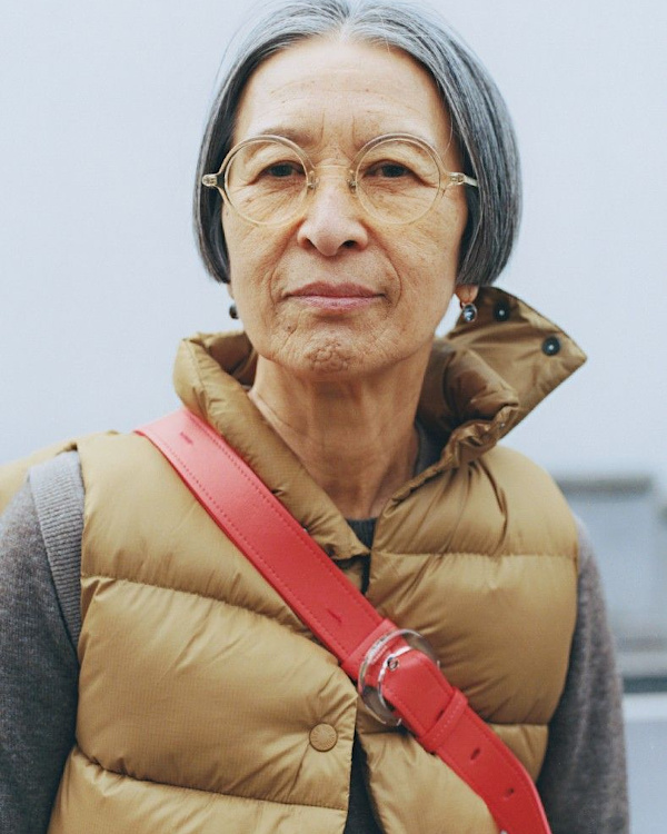 Portrait d’une femme de plus de 60 ans avec lunettes rondes, doudoune sans manches et sac bandoulière coloré