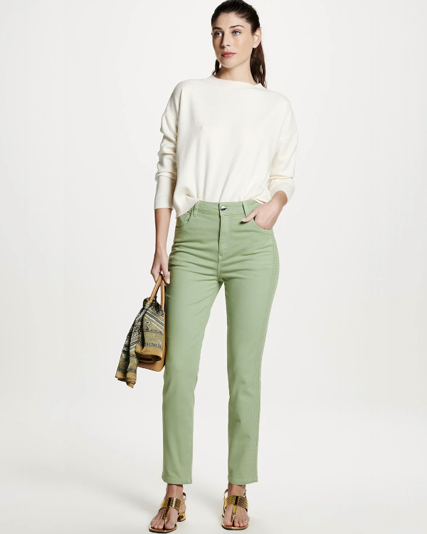 Slim vert d'eau associé à un pull écru, des sandales dorées à petit talon et un foulard imprimé tenu à la main