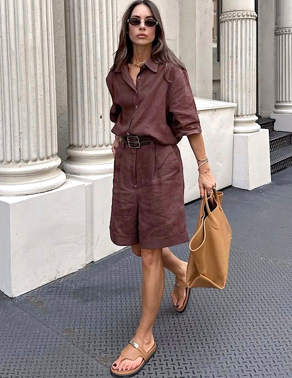 Femme portant un ensemble bermuda et chemise marron avec des sandales plates et un grand sac camel