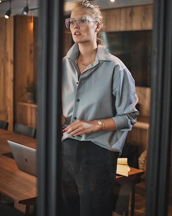 Style professionnel contemporain avec chemise bleu gris, pantalon sombre et lunettes de vue