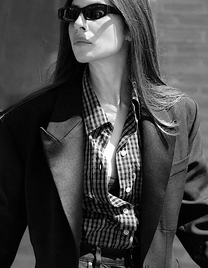 Blazer noir, chemise à carreaux et lunettes de soleil