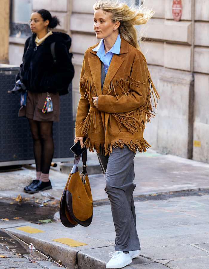 Veste en daim camel à franges portée avec un pantalon gris
