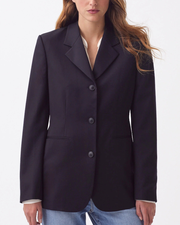 Blazer bleu marine à trois boutons et épaules structurées, porté avec un jean bleu clair